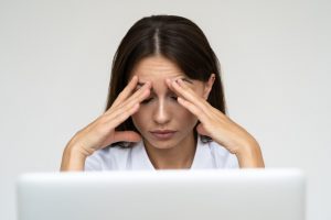 a woman whose hands are placed in her head as a sign of work stress