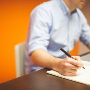 Report Job Discrimination: Man Listing notes on a notebook with yellow background