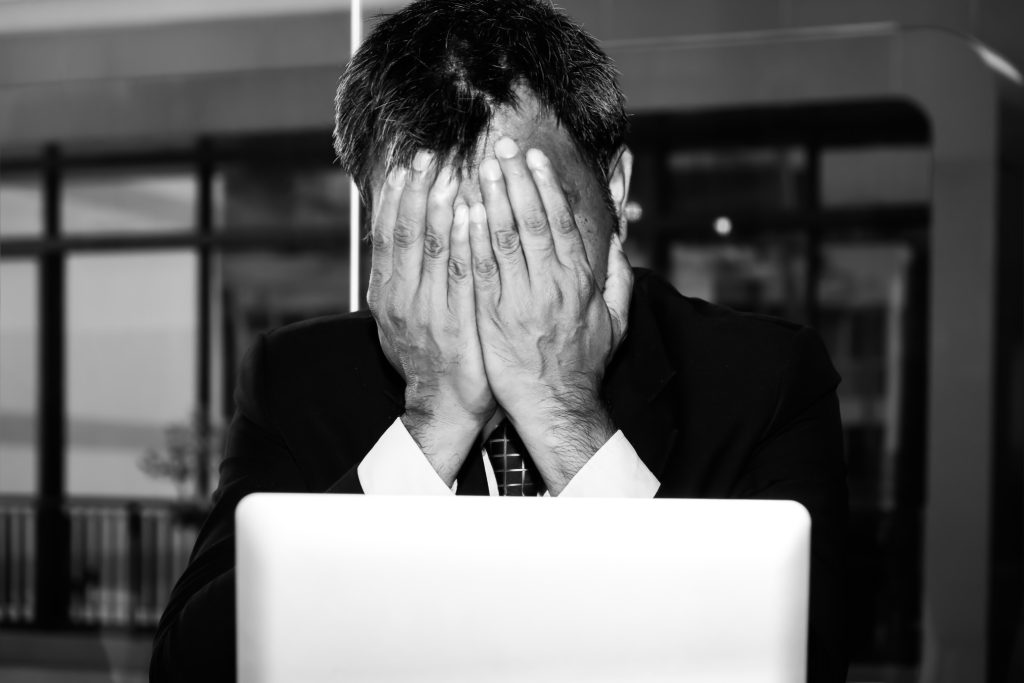 a man covering his face with his hands in disappointment as he faces job discrimination