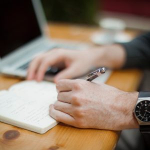 a man in sleeves writing in a planner and choosing from the productivity apps option