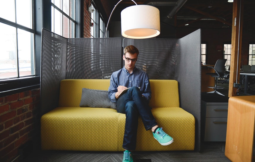 a man sitting pretty in a couch browsing for the best resume writing services to hire