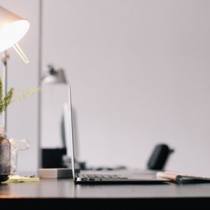 A clean and tidy work space with lamp and laptop to conquer job boredom