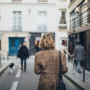 A short haired woman in square patterned coat walking in the streets to look for a successful career change