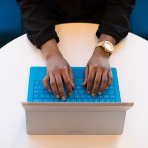 A woman wearing long sleeves is writing objectives for resume in her laptop