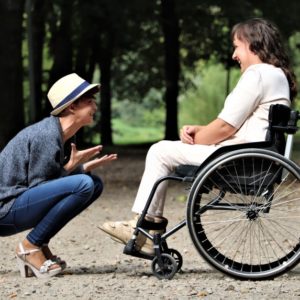 Happy woman sitting in front of a woman in a wheelchair telling about careers for people with disabilities