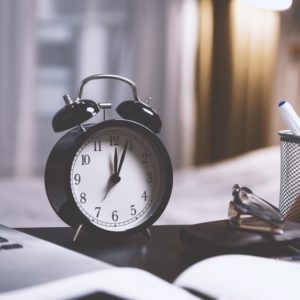 Clock, pens, paper, and laptop of someone who wants to write a resume in minutes