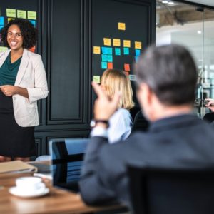 A smiling woman discussing a effective resume writing strategy to her teammates