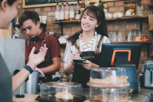 Smiling female hourly worker taking customer orders