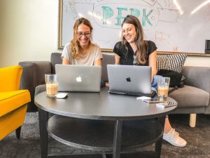 Two ladies looking for online job search tools using their macbook