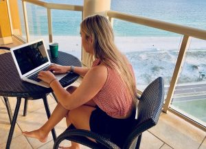 Girl writing a resume while on summer vacation on the beach