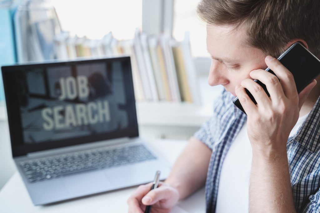 job seeker looking for posts online while talking on the phone