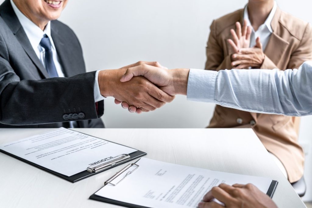 A male candidate with good job interview body language shaking hands with employer