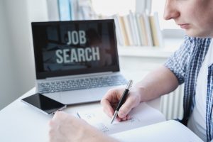 Man taking notes while searching for job during unemployment period