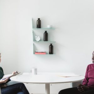 A male job seeker answers job interview questions from a female interviewer in a meeting room