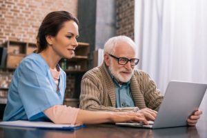 Medical assistant assisting patient in laptop.