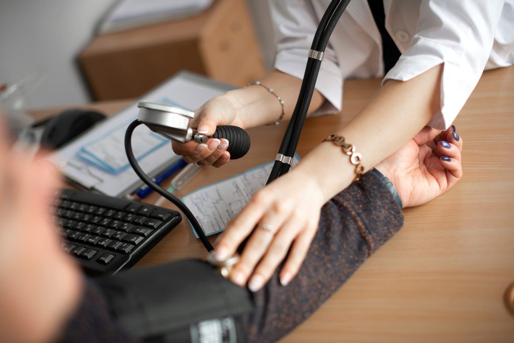 medical assistant checking patient’s blood pressure