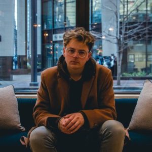 Millennial man seated in the middle of the couch to answer a dreaded interview question