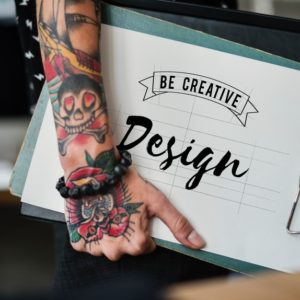 tattooed arms carrying creative resumes and portfolio