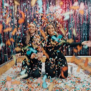 Two woman enjoying the party game ideas with a lot of colorful confetti