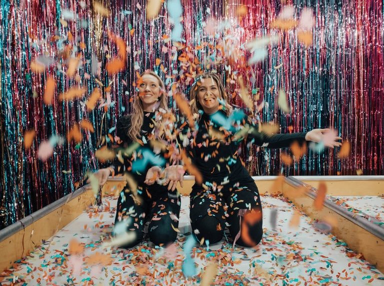 Two woman enjoying the party game ideas with a lot of colorful confetti