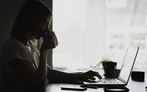 Lady drinking coffee while browsing on laptop