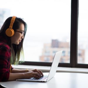 Woman with yellow headset and cover letter writing skills typing in her laptop