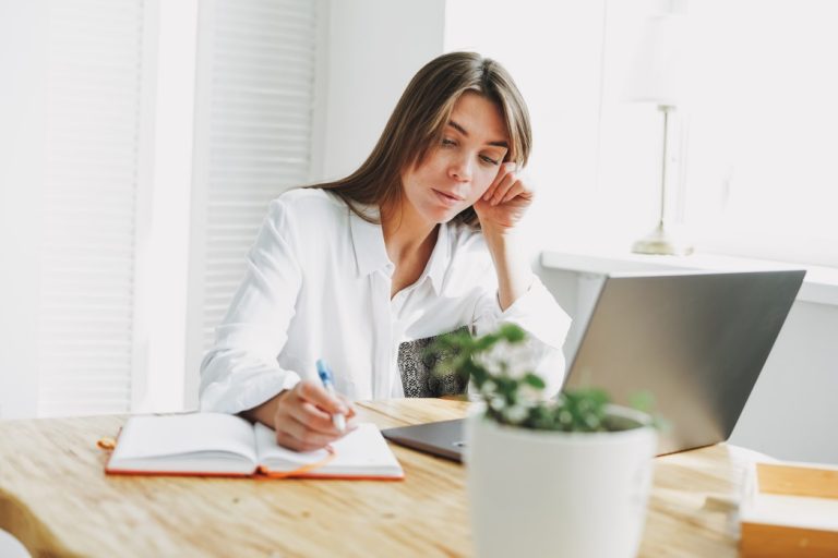 woman searching about words to describe yourself in a resume and writing it in a notebook